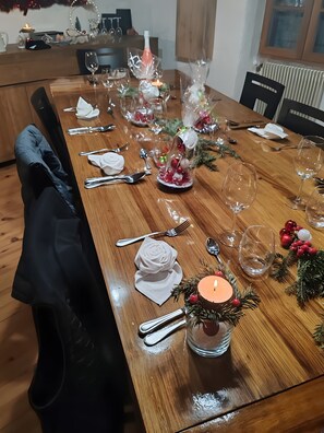 Ein Esstisch, gedeckt mit GlÀsern, Besteck und einer Kerzenarragement.