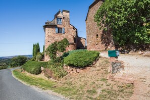 A stone building with a small tower, a mailbox, and a road curving to the left. - Sans Chichi Chambre Nature (Escandolières)