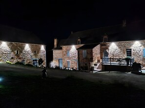 Un edificio de piedra con porche y escalones, iluminado con luces exteriores.