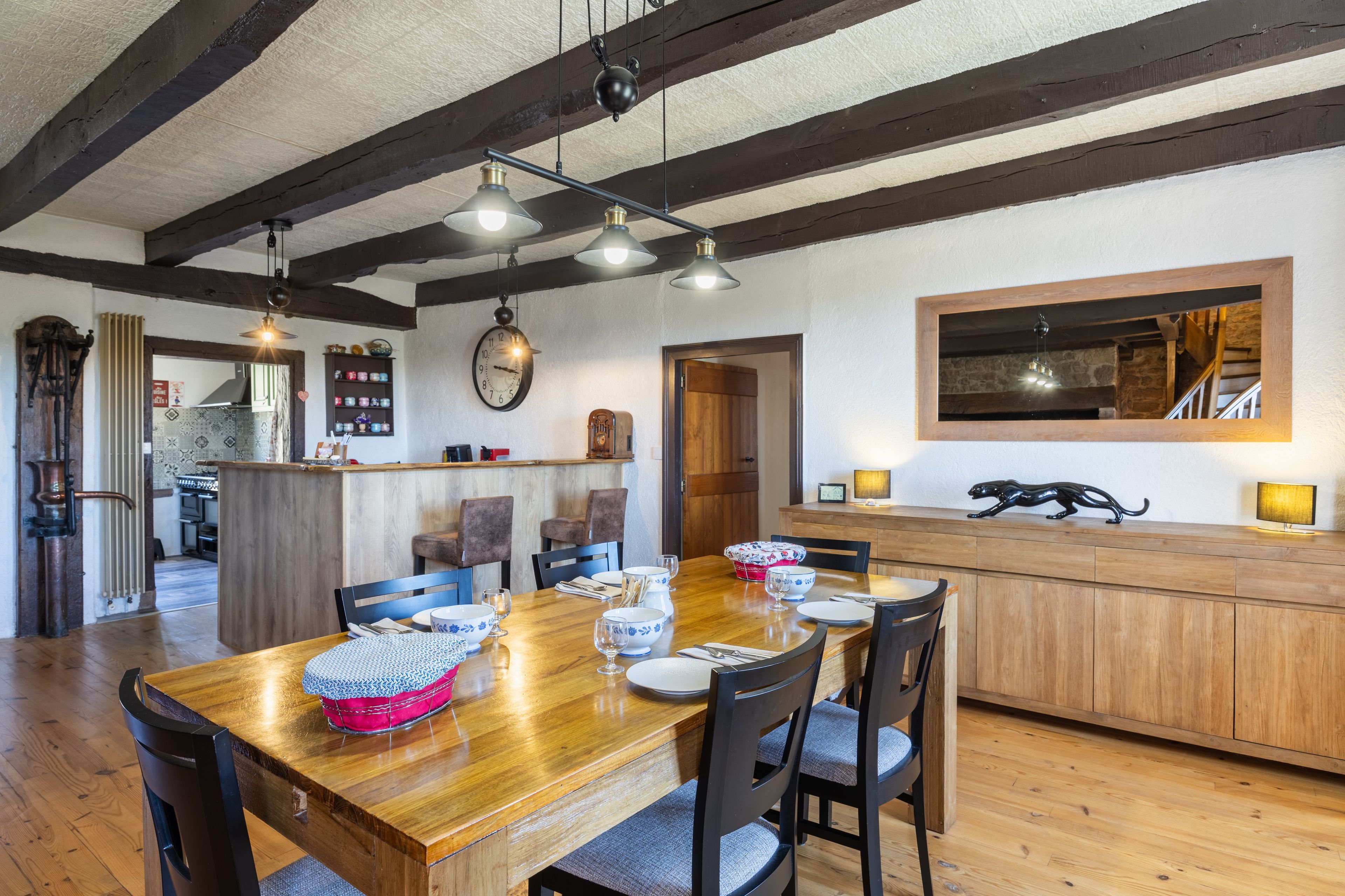 Zona pranzo con tavolo in legno, sedie e una cucina sullo sfondo.