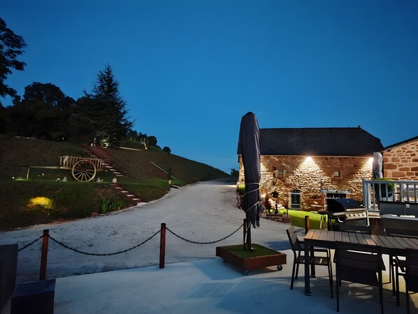 Ein GebĂ€ude aus Stein mit einer RollstuhlerhebebĂŒhne, AuĂenbestuhlung und einem Grillplatz.