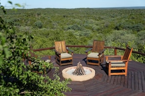 A deck with wooden chairs and a fire pit. - Parsons House (Hoedspruit)
