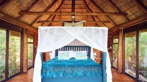 A room with a bed under a canopy, wooden walls, and large windows. - Parsons House (Hoedspruit)