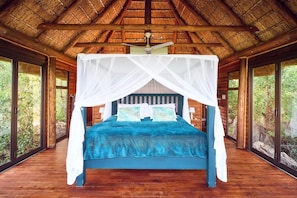 A room with a bed under a canopy, wooden walls, and large windows. - Parsons House (Hoedspruit)