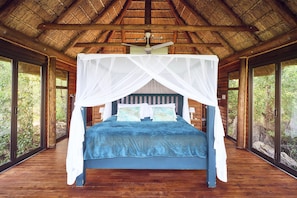 A room with a bed under a canopy, wooden walls, and large windows. - Parsons House (Hoedspruit)