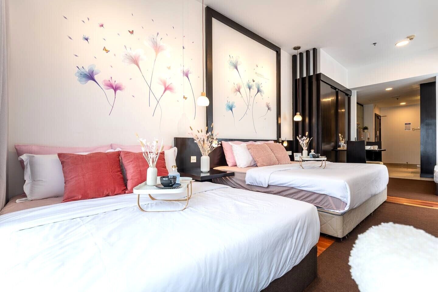 Una habitación de hotel con dos camas, un espejo grande y una pared decorada con motivos florales.