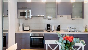 Une cuisine moderne avec des meubles gris, un four à micro-ondes, une cuisinière et un évier.