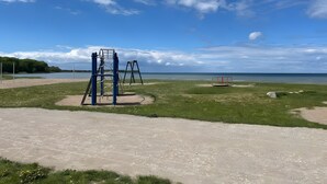 Une aire de jeux avec des balançoires et une structure d’escalade, située près d’un plan d’eau.