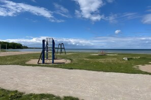 A playground with swings and a climbing structure near a body of water.