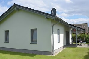 A modern house with a satellite dish, a covered porch, and a well-maintained lawn. - Vacation Home "Sandbank" in Zierow on the Baltic Sea (Zierow)