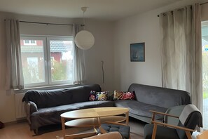 Una sala de estar moderna con un sofá gris, una mesa de centro de madera y un sillón gris.