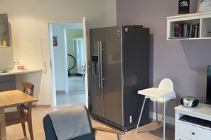 Une cuisine compacte équipée d’un réfrigérateur moderne, d’une table à manger et d’une chaise haute.
