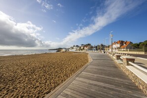 A wooden boardwalk leading to a sandy beach with houses in the background. - Near beach, flat 2 adults 2 children (Saint-Hilaire-de-Riez)