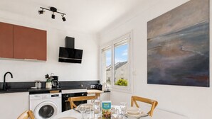 Eine moderne Küche mit Waschmaschine, einer Essecke für vier Personen, gedecktem Tisch und einem großen, abstrakten Gemälde an der Wand.
