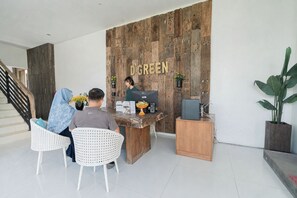 A reception desk with a wooden backdrop, a staircase, and a potted plant. - D' Green Nirava By Reccoma (Kabupaten Badung)