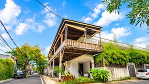 A two-story building with a balcony, surrounded by greenery and parked cars. - D' Green Nirava By Reccoma (Kabupaten Badung)