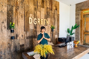 Un mostrador de recepción de madera con un letrero que dice 'D GREEN' y una persona de pie detrás.