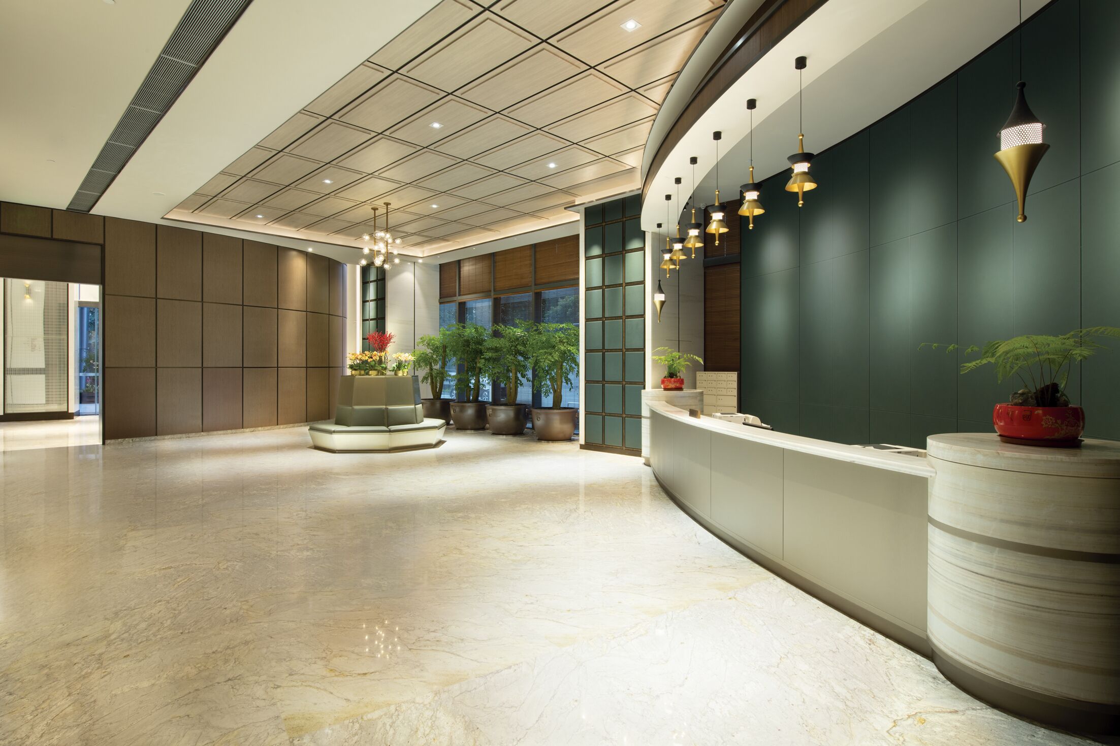A spacious lobby with a marble floor, a reception desk, potted plants, and pendant lighting.