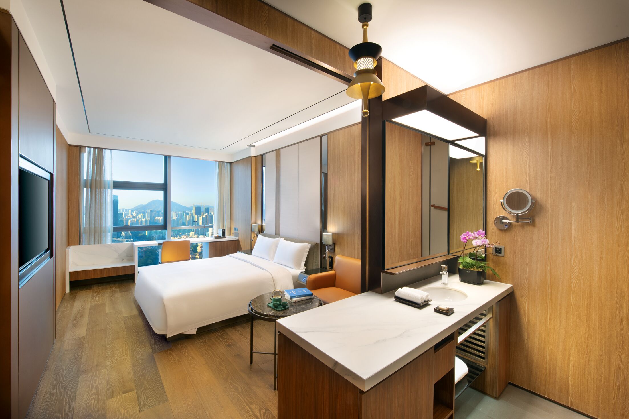 Habitación de hotel con cama, escritorio, baño con espejo y vistas a la ciudad.