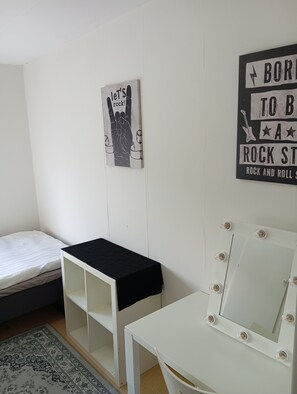 A room with a bed, a small table with a black tablecloth, a vanity with lights, and two wall decorations. - Charming 2-bedroom Apartment in Historic Skara, Sweden (Skara)