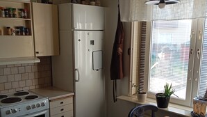 Una cocina con estufa, horno, refrigerador y mesa de comedor.