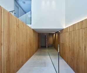 A modern interior with wooden panel walls, a glass door, and a concrete floor. - Fontana | The Rentals Collection (San Sebastián)