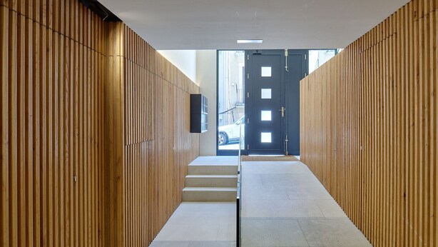 A hallway with wooden paneling, a door at the end, and a car visible outside. - Fontana | The Rentals Collection (San Sebastián)