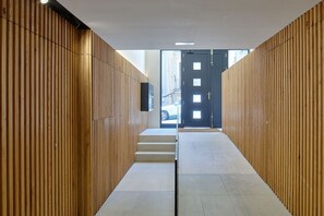 A hallway with wooden paneling, a door at the end, and a car visible outside. - Fontana | The Rentals Collection (San Sebastián)