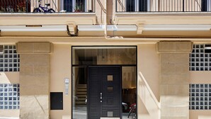A building facade with a black door, a visible staircase, and a numbered window. - Fontana | The Rentals Collection (San Sebastián)