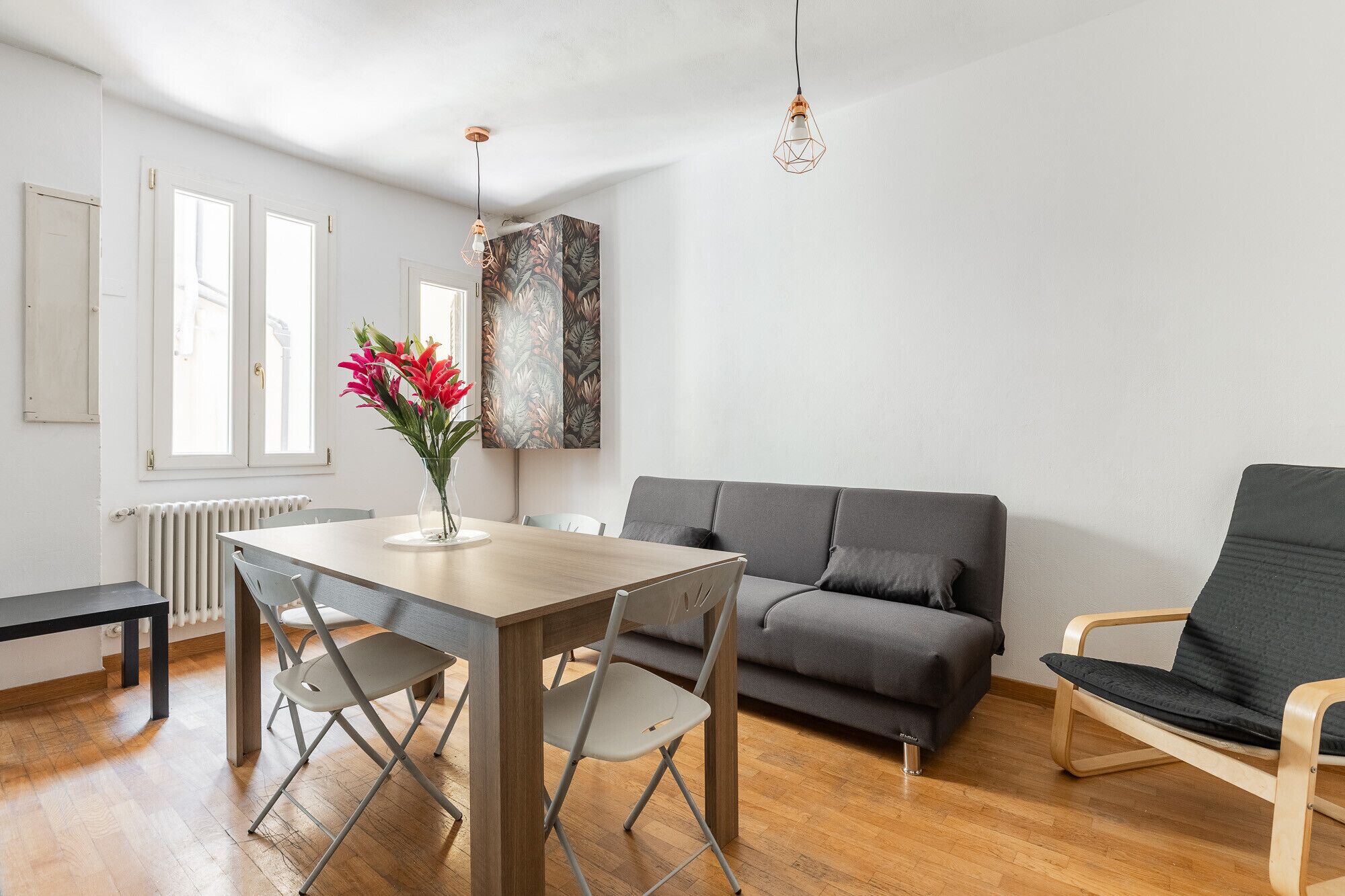 Un salon moderne avec une table à manger en bois, un canapé gris et un fauteuil gris.