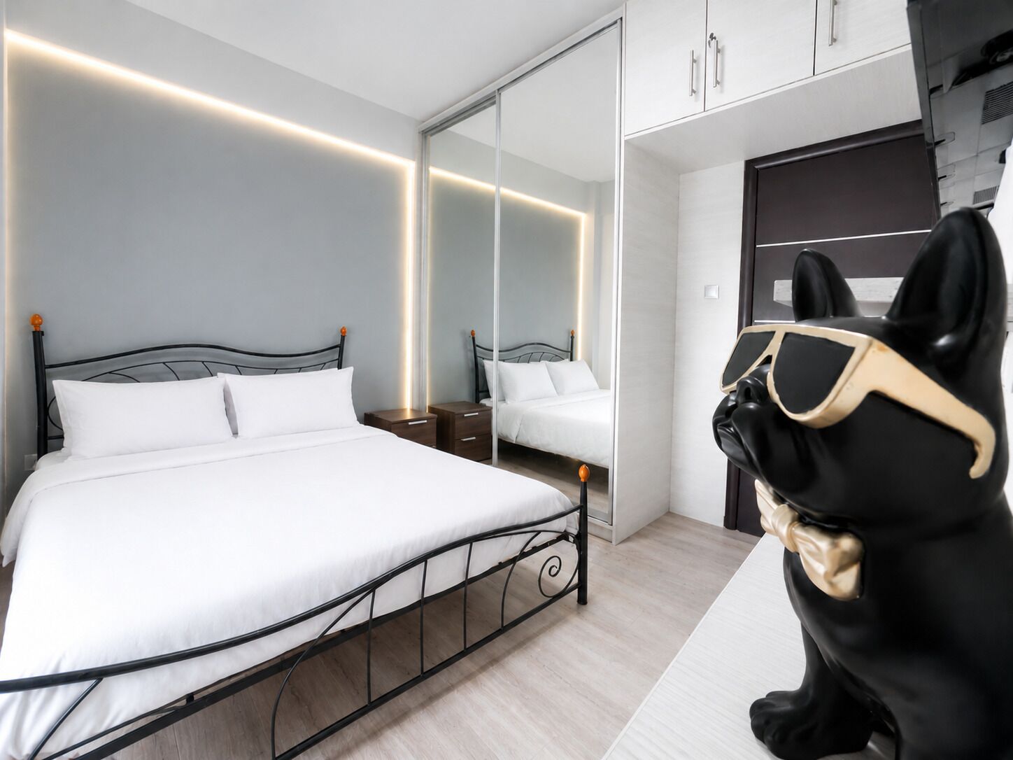 Habitació d'hotel moderna amb un llit gran, taules de nit, un armari i un mirall.
