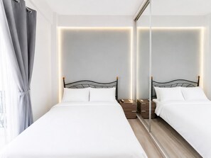 Une chambre d’hôtel avec deux lits, un grand miroir, des tables de chevet et un panneau mural éclairé.