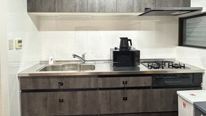 A modern kitchen with a stainless steel countertop, a built-in microwave, a coffee maker, and a gas stove. - Spacious 5BR Asakusa Riverside House near Sensoji & Skytree (Taito-Ku)