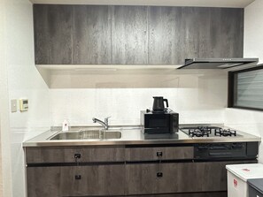 A modern kitchen with a stainless steel countertop, a built-in microwave, a coffee maker, and a gas stove. - Spacious 5BR Asakusa Riverside House near Sensoji & Skytree (Taito-Ku)