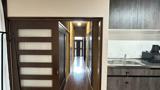 A hallway leading to a kitchen with wooden flooring, a sink, and cabinets. - Spacious 5BR Asakusa Riverside House near Sensoji & Skytree (Taito-Ku)