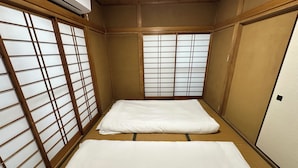 A traditional Japanese room with tatami flooring, shoji screens, and a futon bed. - Spacious 5BR Asakusa Riverside House near Sensoji & Skytree (Taito-Ku)