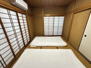 A traditional Japanese room with tatami flooring, shoji screens, and a futon bed. - Spacious 5BR Asakusa Riverside House near Sensoji & Skytree (Taito-Ku)