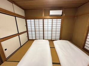 A traditional Japanese room with tatami flooring, shoji screens, and a ceiling-mounted air conditioner. - Vrbo Property (台東区)