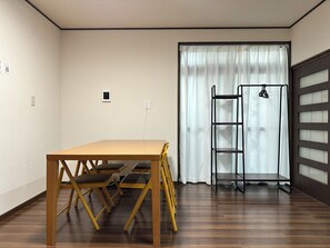 A room with a wooden table and chairs, a ladder, and a window with curtains. - Vrbo Property (台東区)