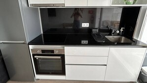 Eine kompakte Küche mit Kühlschrank, Backofen, Spüle und einer schwarzen Arbeitsplatte.