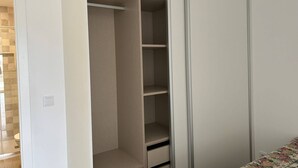 Ein begehbarer Kleiderschrank mit mehreren Regalen und einer Schiebetür.