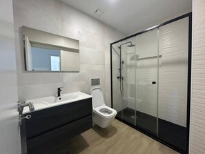 A modern bathroom with a toilet, sink, and shower. - Apartamento T2 com Terraço (Coimbra)