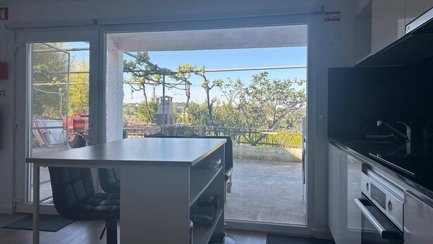 Eine moderne Küche mit großem Fenster, einem Essbereich mit Tisch und Stühlen sowie einem Einbauofen.