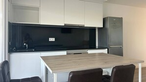 Eine moderne Küche mit weißen Schränken, einer schwarzen Arbeitsplatte und einem eingebauten Kühlschrank.