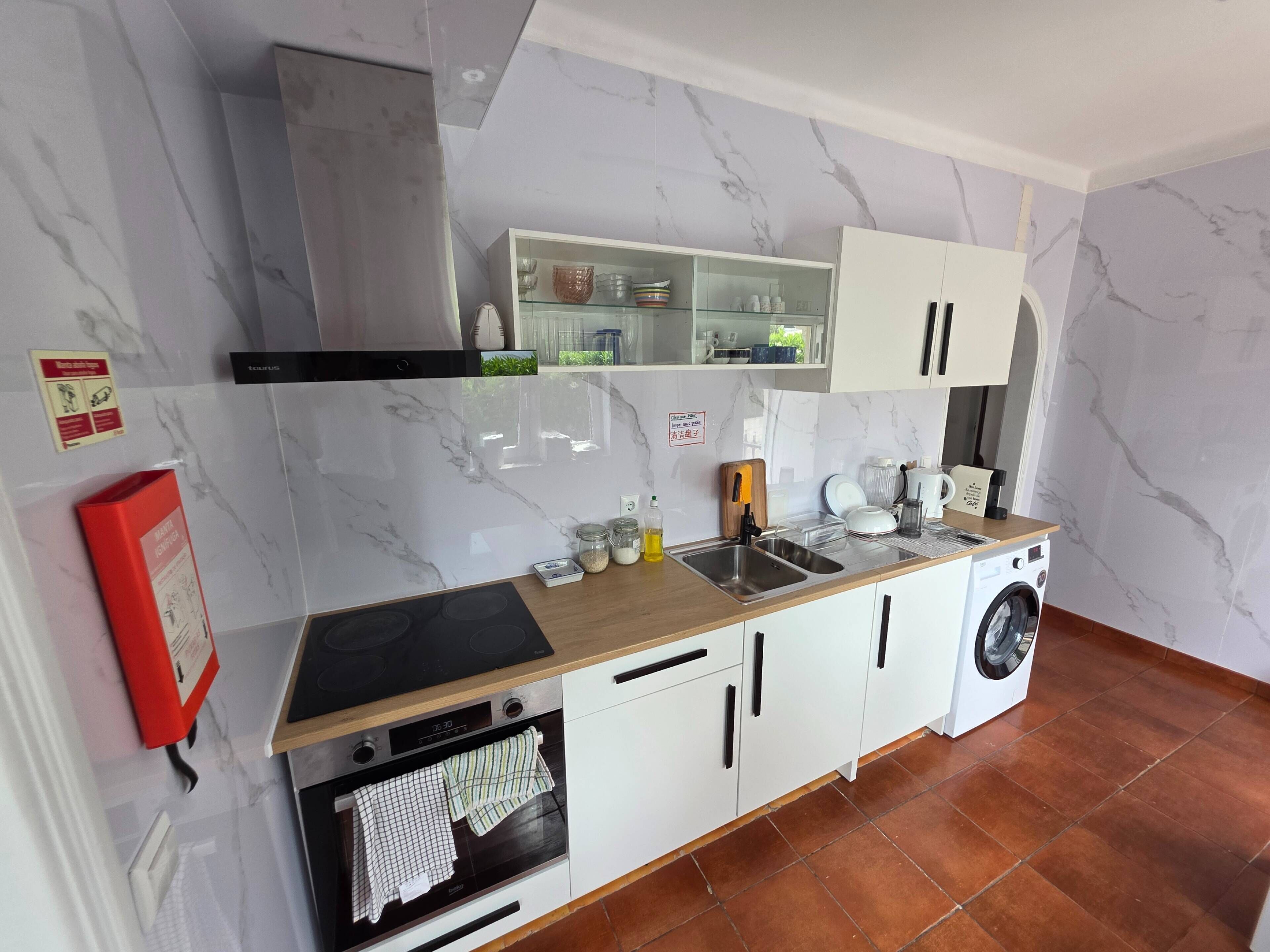A modern kitchen with a built-in oven, microwave, and washing machine.