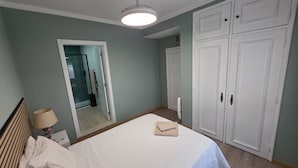 A bedroom with a bed, a wardrobe, a mirror, and a ceiling light. - Quarto Suite Hope Vista Jardim (Coimbra)