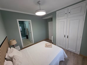 A bedroom with a bed, a wardrobe, a mirror, and a ceiling light. - Quarto Suite Hope Vista Jardim (Coimbra)