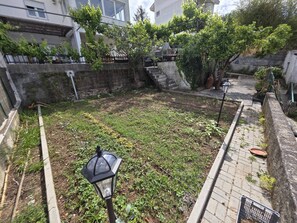 A courtyard with a paved walkway, a lamp post, and a small garden area with plants. - Quarto Suite Hope Vista Jardim (Coimbra)