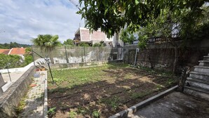 Un jardín en la azotea con un camino de hormigón, una valla de metal y una escalera.