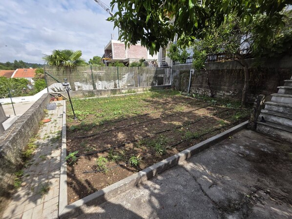 Un jardin aménagé sur le toit, avec un chemin en béton, une clôture en métal et un escalier.